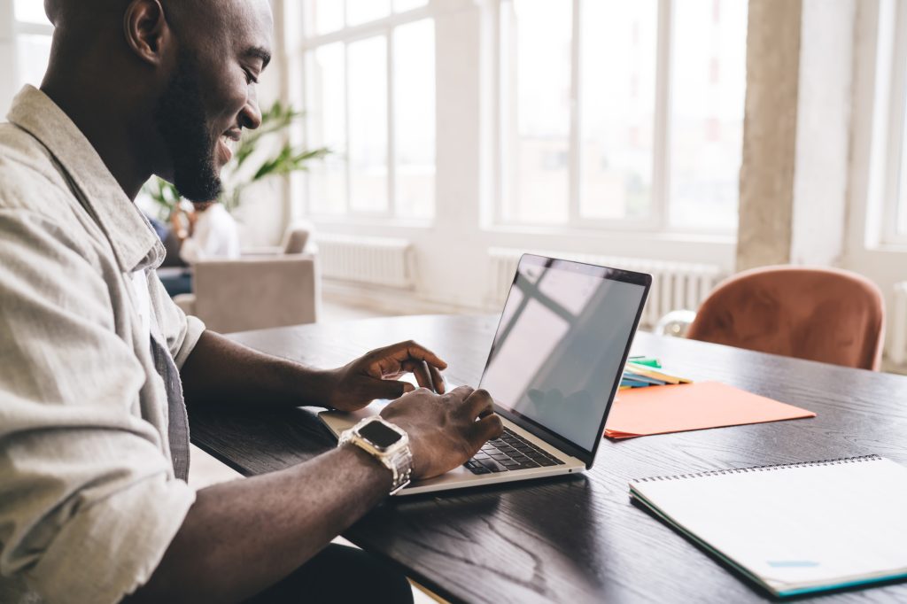 Black man working on laptop sitting at table during work